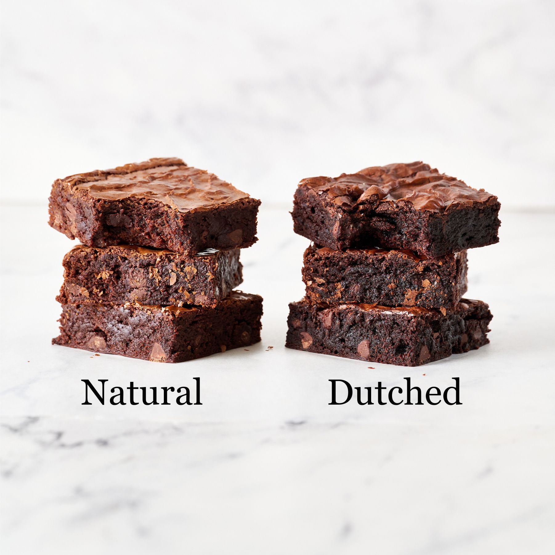 brownies on the left made with natural cocoa, two brownies on the right made with Dutched cocoa, all on a marble surface