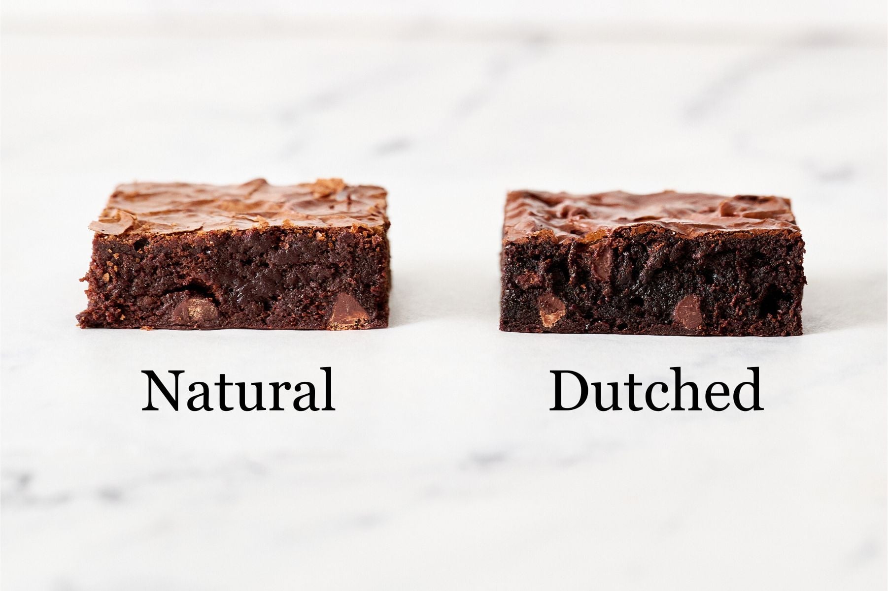 one brownie on the left made with natural cocoa, one on the right made with Dutch process, on a marble counter