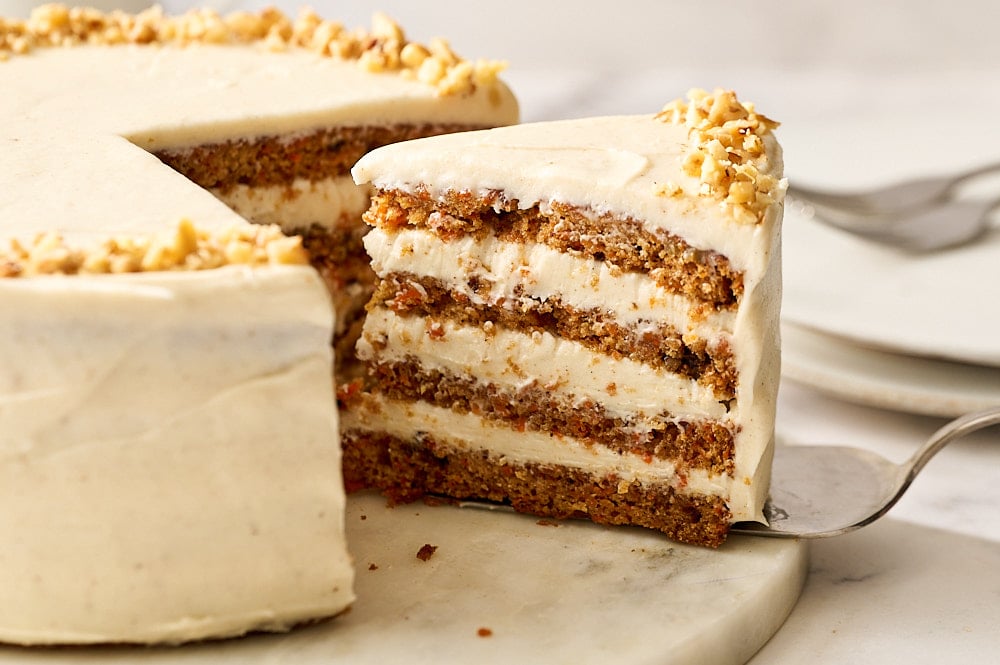 carrot cake slice on cake server being pulled from whole cake