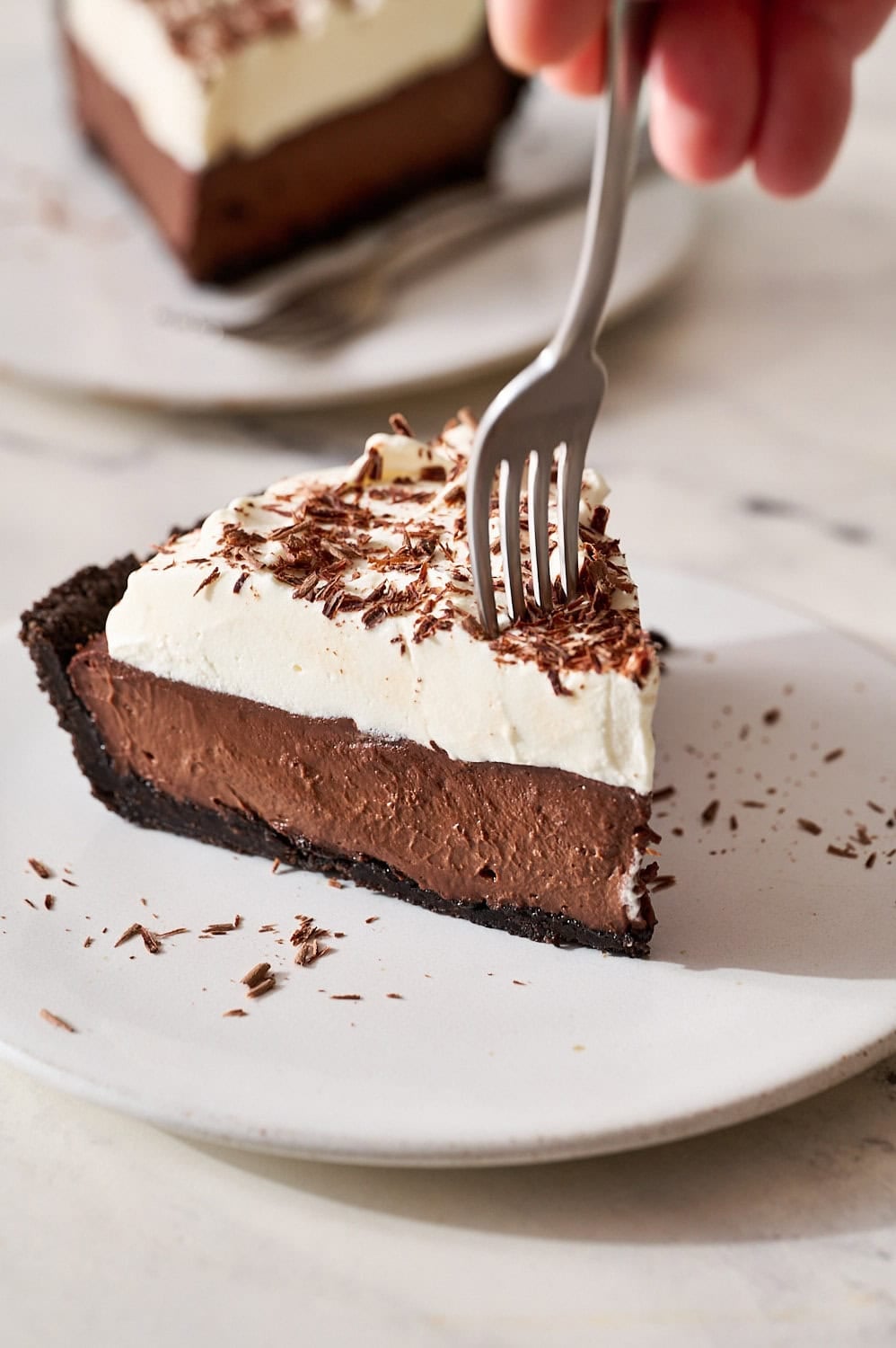 slice of chocolate cream pie on a plate with a fork about to take a bite
