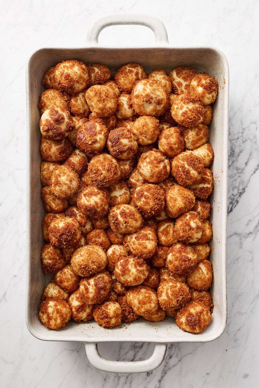 assembled cinnamon bun bites in pan after rising on a marble surface