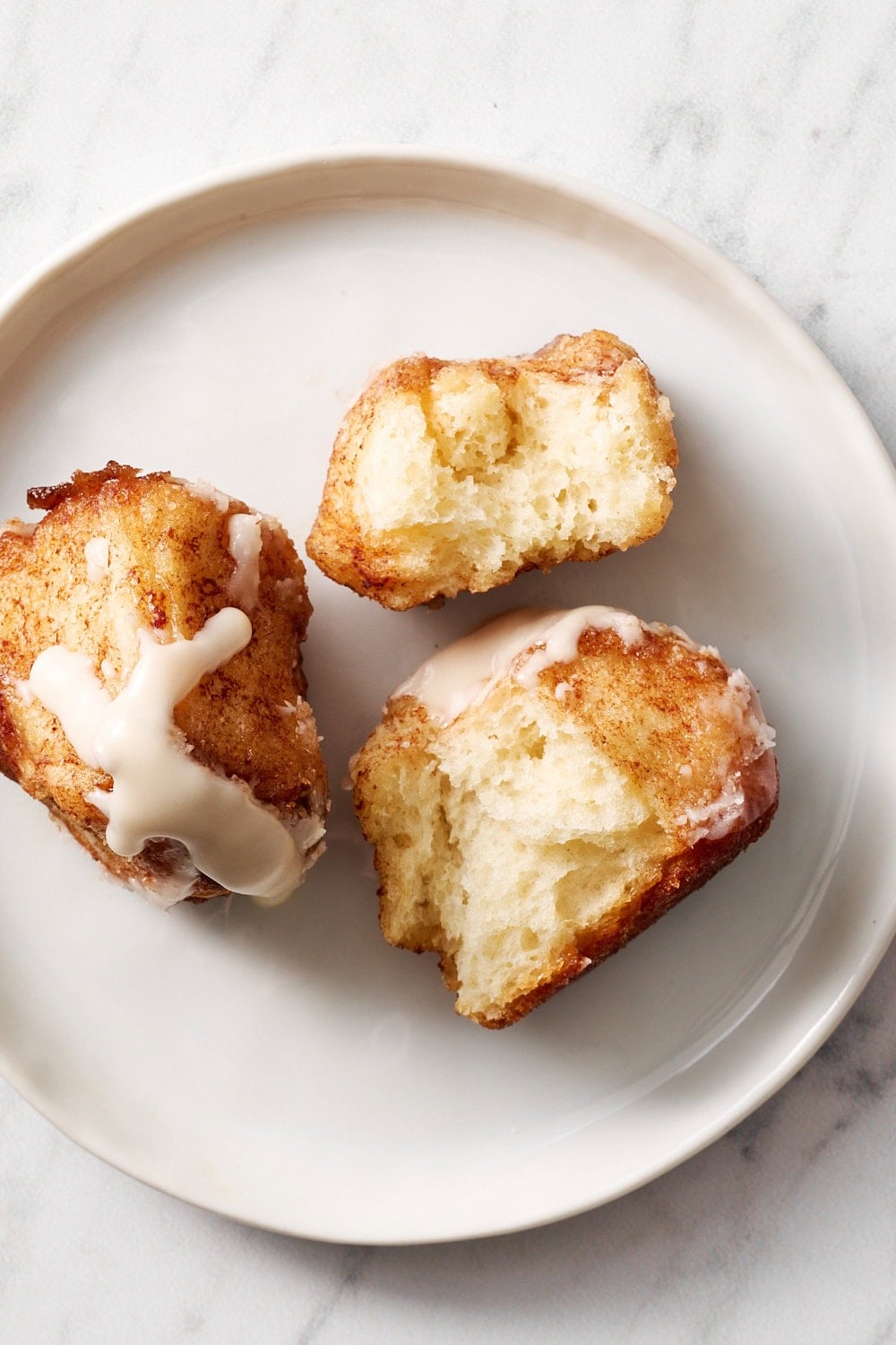 two cinnamon bun bites on a small place, one broken in half to show pillowy interior texture