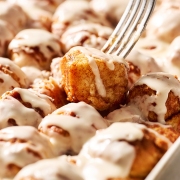 fork lifting up a cinnamon bun bites from the pan to reveal the soft, gooey interior