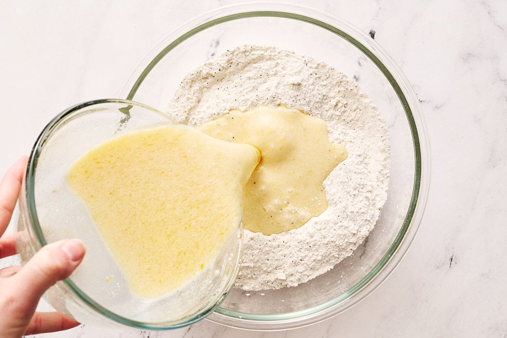 adding wet ingredients to dry ingredients for lemon poppyseed muffins