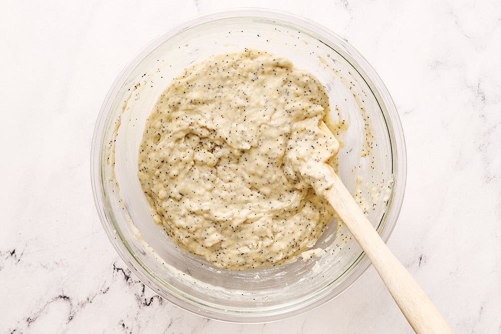 lemon poppyseed muffin batter in glass mixing bowl with spatula