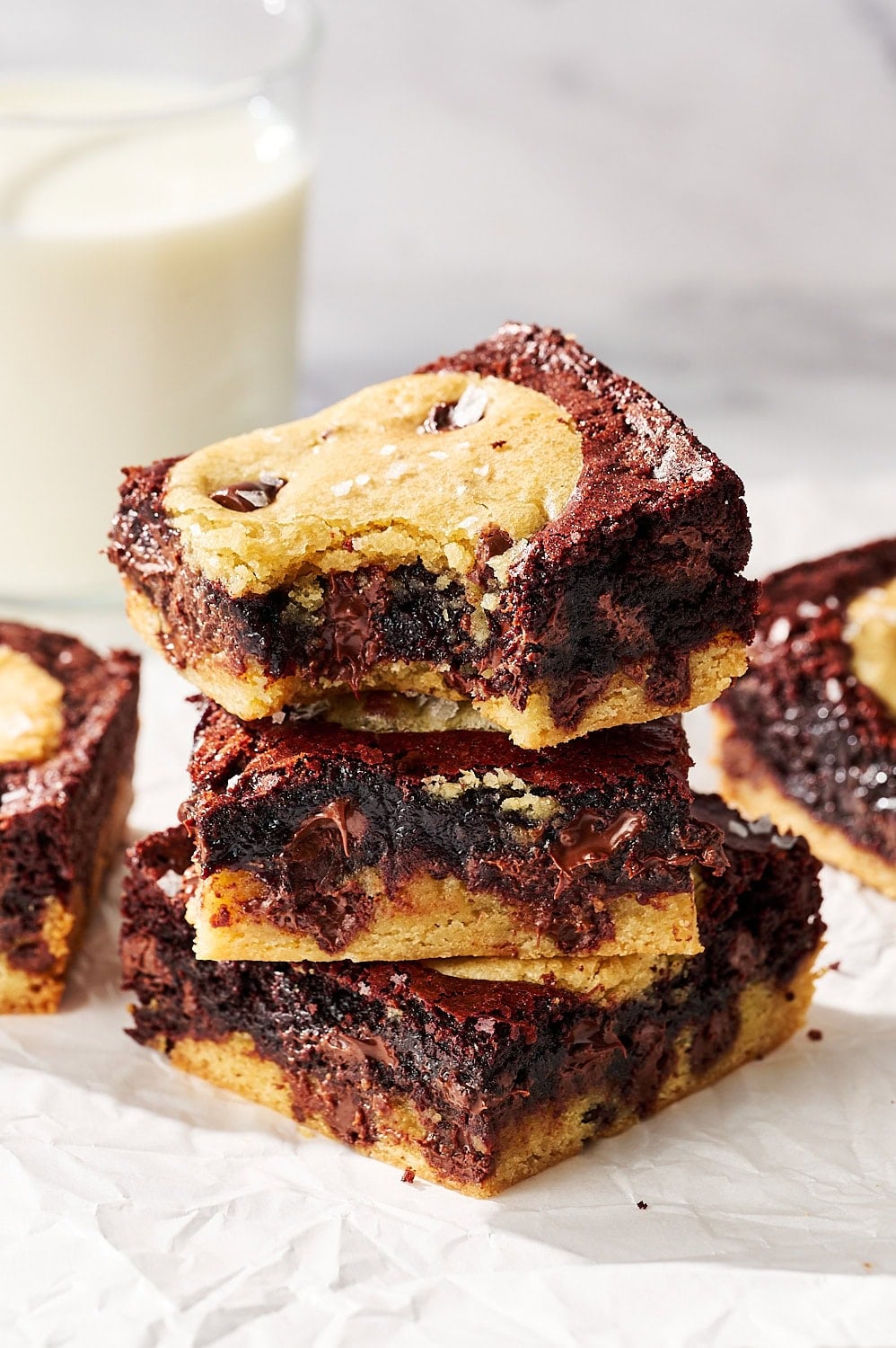 stack of homemade brookies on a piece of parchment with a glass of milk