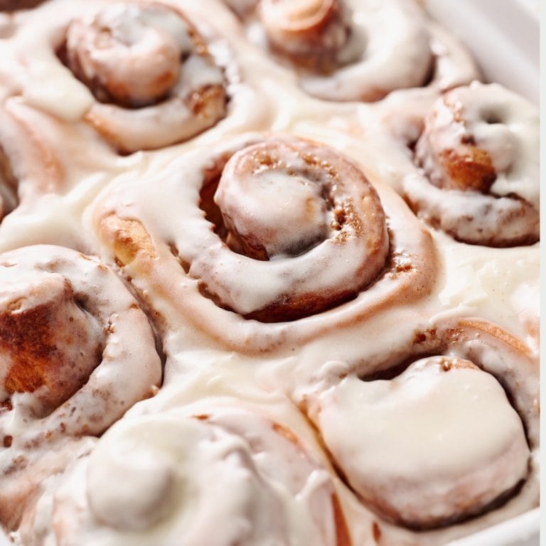 closeup of gooey cinnamon rolls topped with vanilla icing