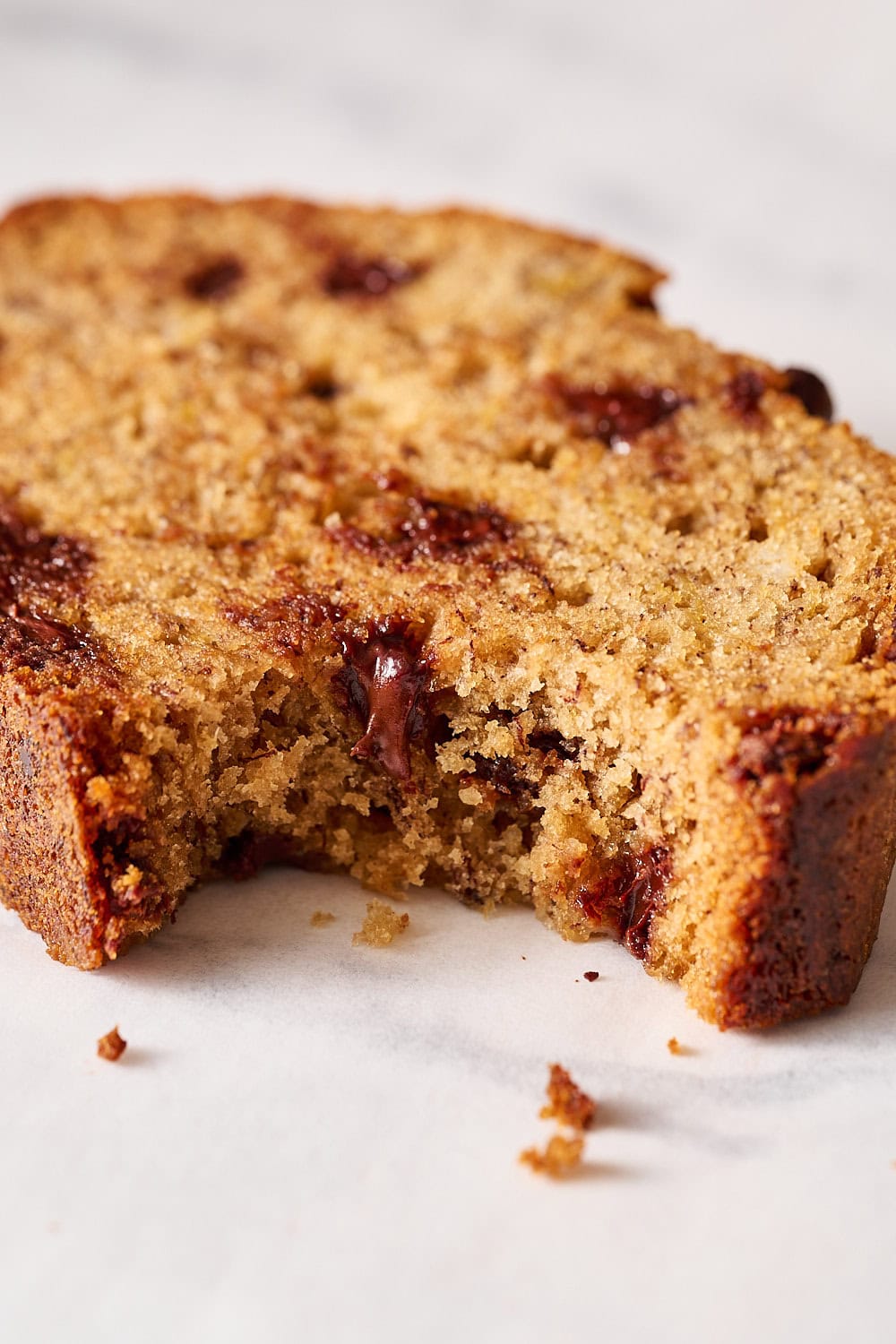 up close shot of a slice of banana bread with a bite taken out to show the gooey chocolate chips inside