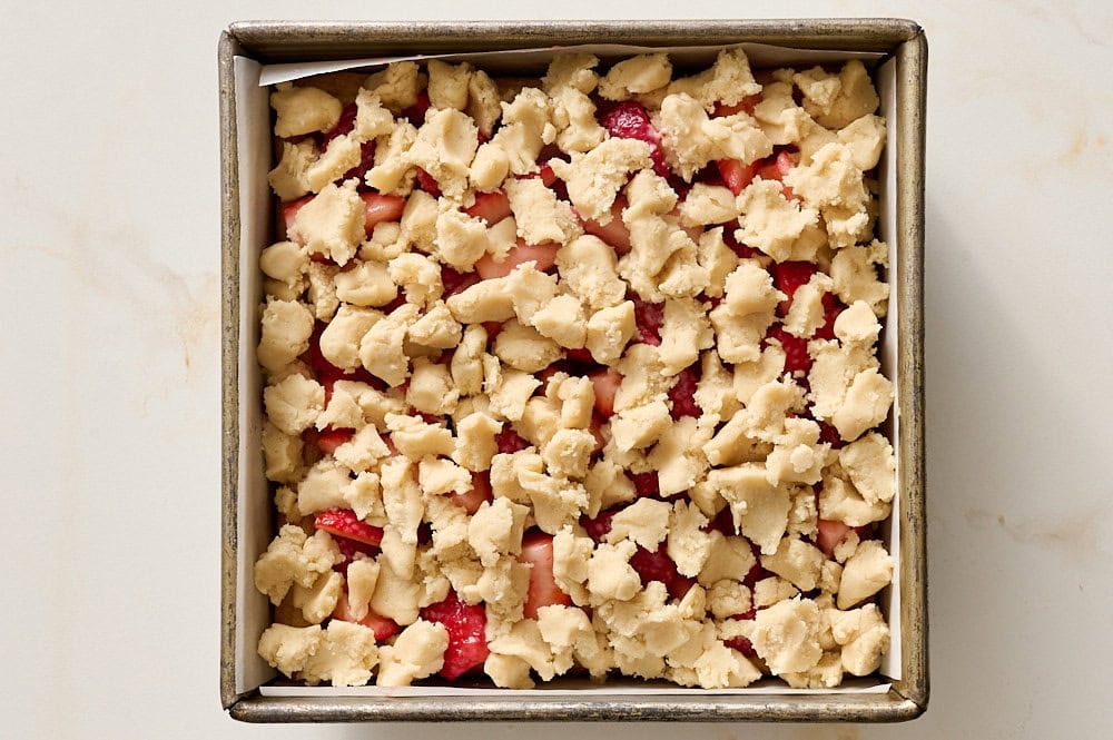 shortbread topped with strawberry mixture and crumbled shortbread dough on top before baking