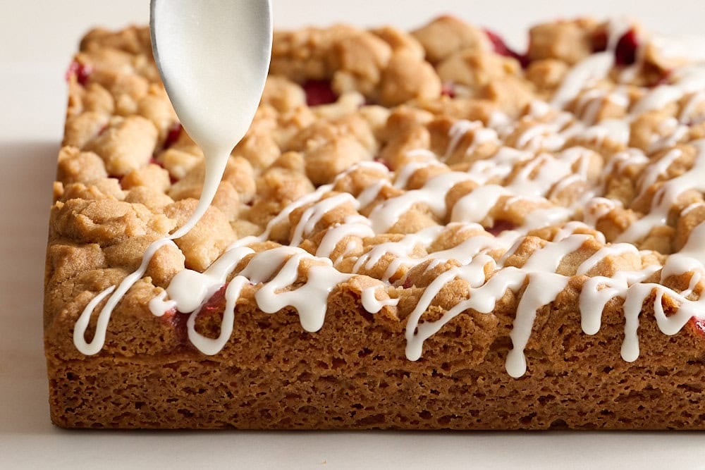 icing cooled strawberry cobbler bars with a spoon
