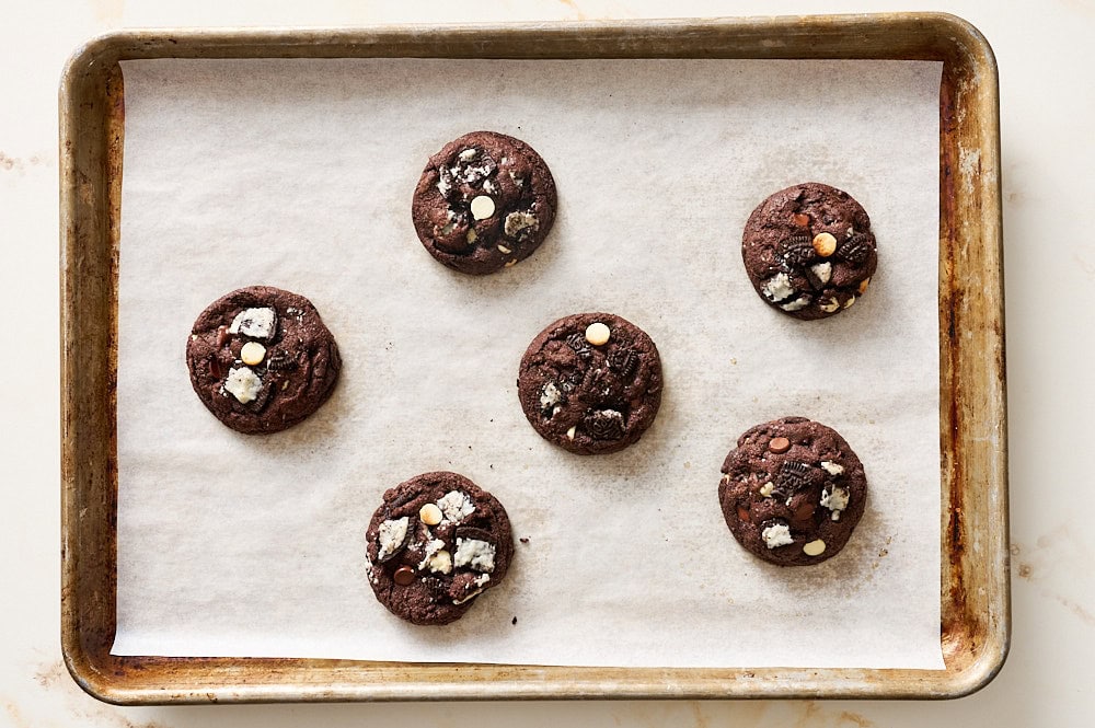 overhead of freshly baked cookies & cream cookies on a parchment lined baking tray