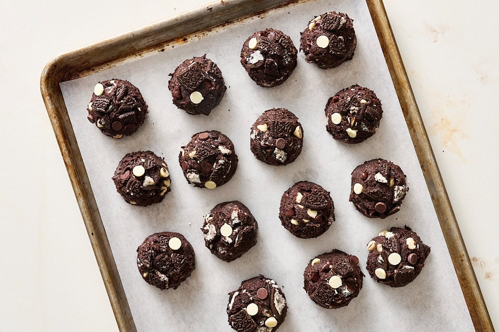 scoops of cookies & cream cookie dough on a parchment lined baking tray