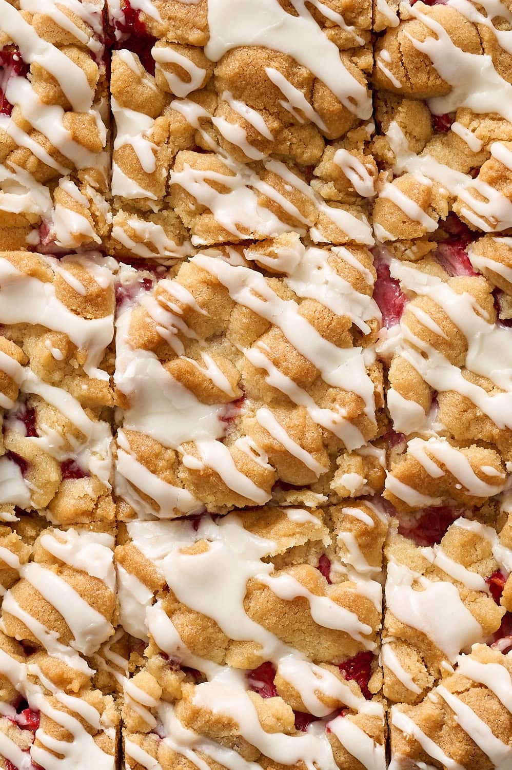 overhead view of sliced strawberry cobbler bars with white icing drizzled on top
