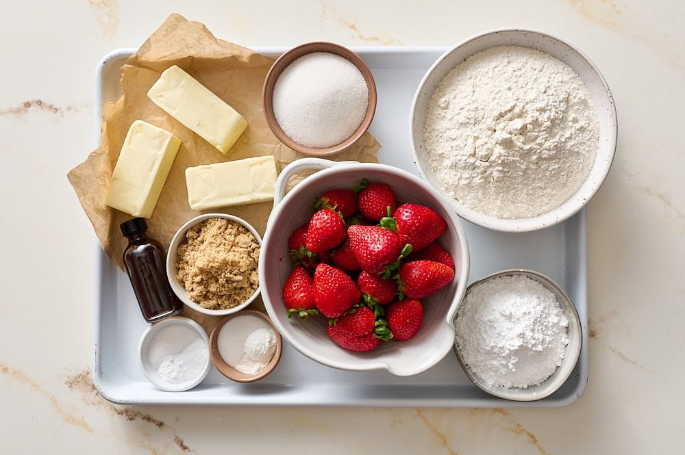 overhead of strawberry cobbler bars ingredients scaled on a white rimmed baking tray