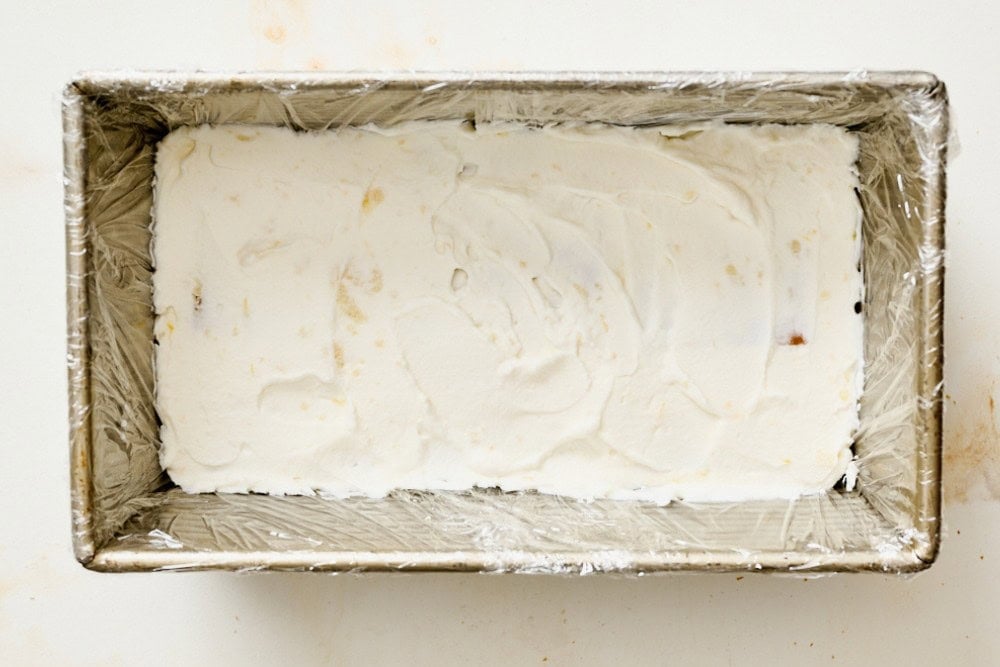 Layer of whipped cream filling spread over graham crackers in a loaf pan