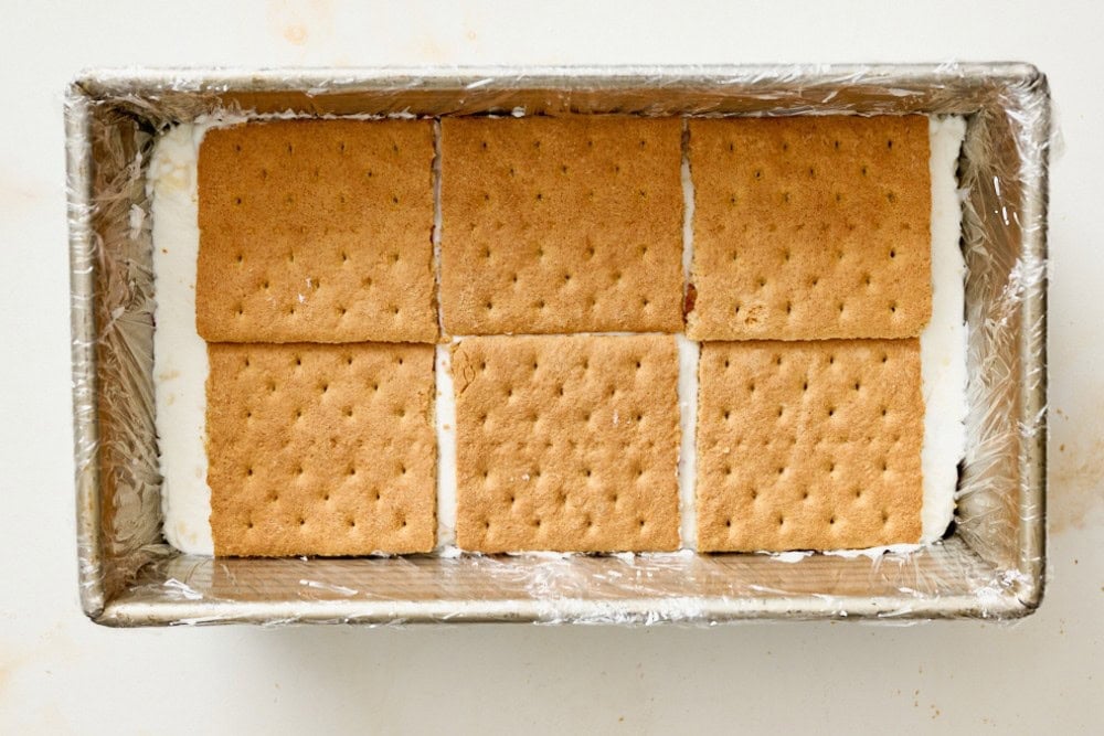 Icebox cake layers with whipped cream filling and graham crackers in a loaf pan