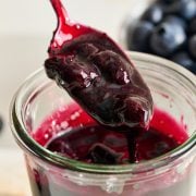 homemade blueberry sauce being spooned into a glass jar