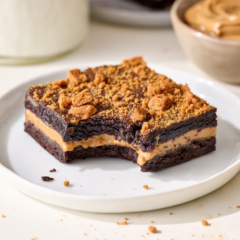 a perfect Biscoff brownie with a bite taken out on a small white plate