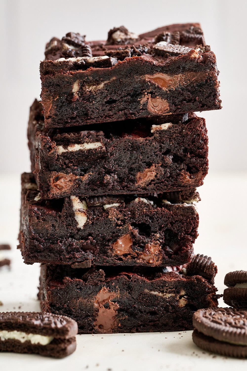 stack of four tall and fudgy Oreo brownies, with extra Oreo cookies nearby