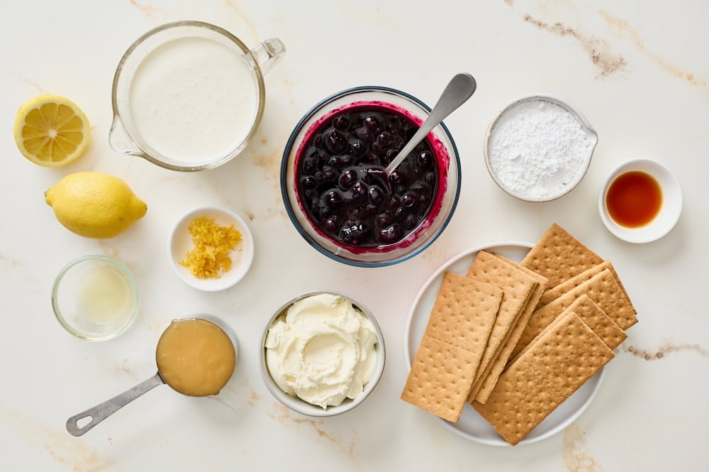 overhead view of all blueberry lemon icebox cake ingredients on a marble countertop