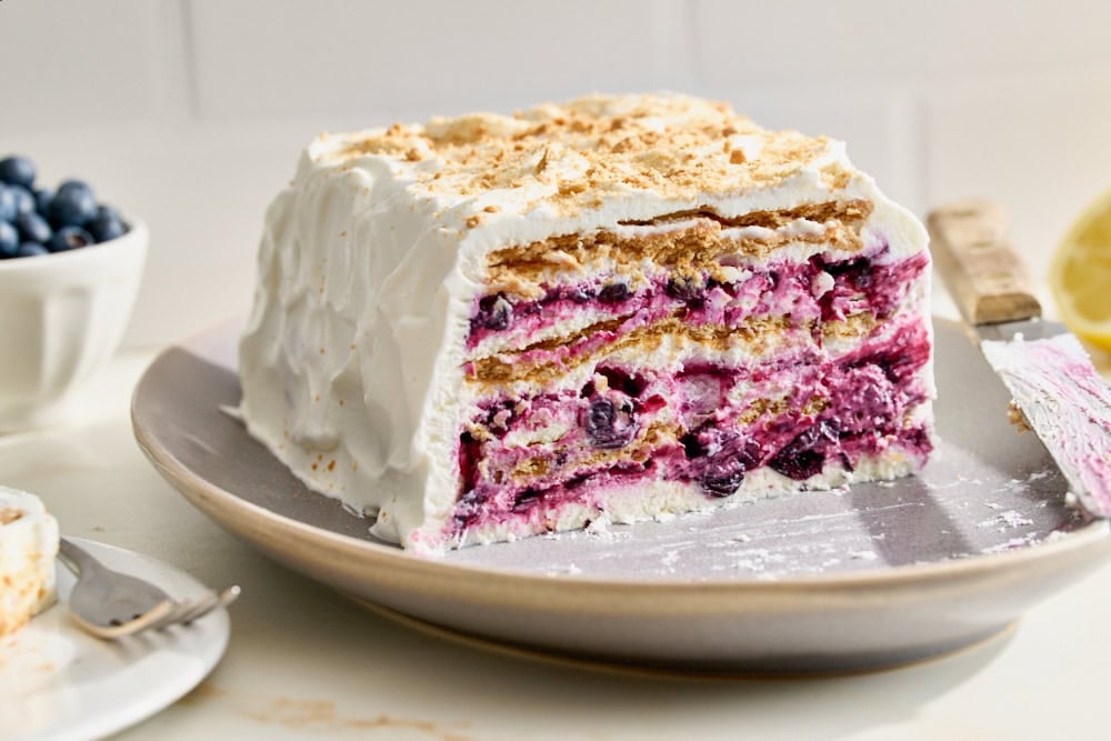 blueberry lemon icebox cake on a platter with a couple slices already removed
