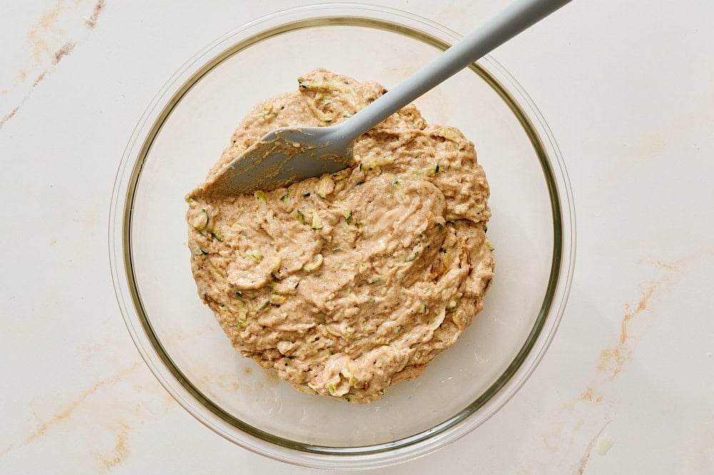 overhead view of the muffin batter in a glass bowl with a silicone spatula