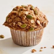a single tall zucchini apple muffin on a white surface