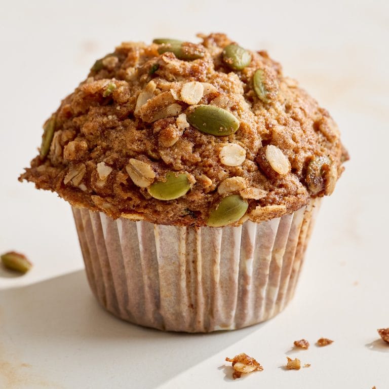 a single tall zucchini apple muffin on a white surface