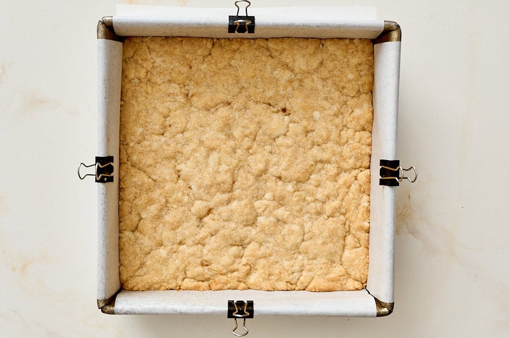 overhead view of par baked shortbread crust in pan for apple pie bars