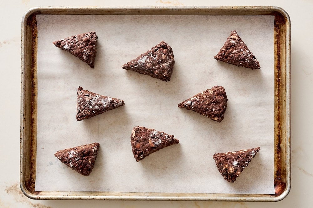 overhead view of unbaked triangles of scone dough on a parchment lined baking tray