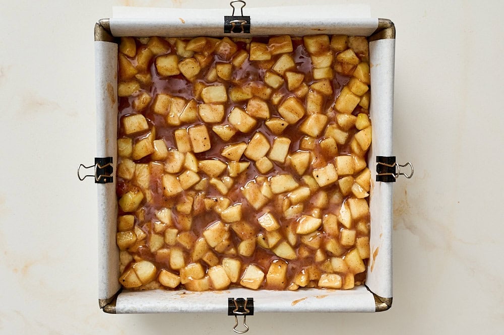 overhead view of apple pie filling spread evenly over shortbread crust in baking pan