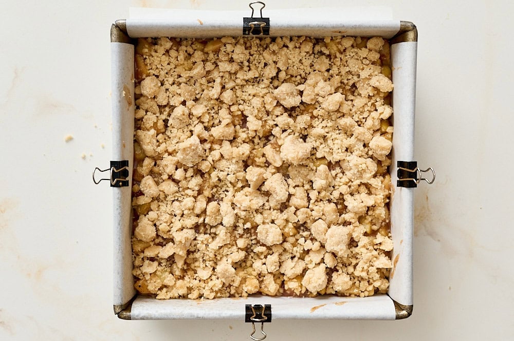 overhead view of shortbread crumbled over apple pie filling in baking pan