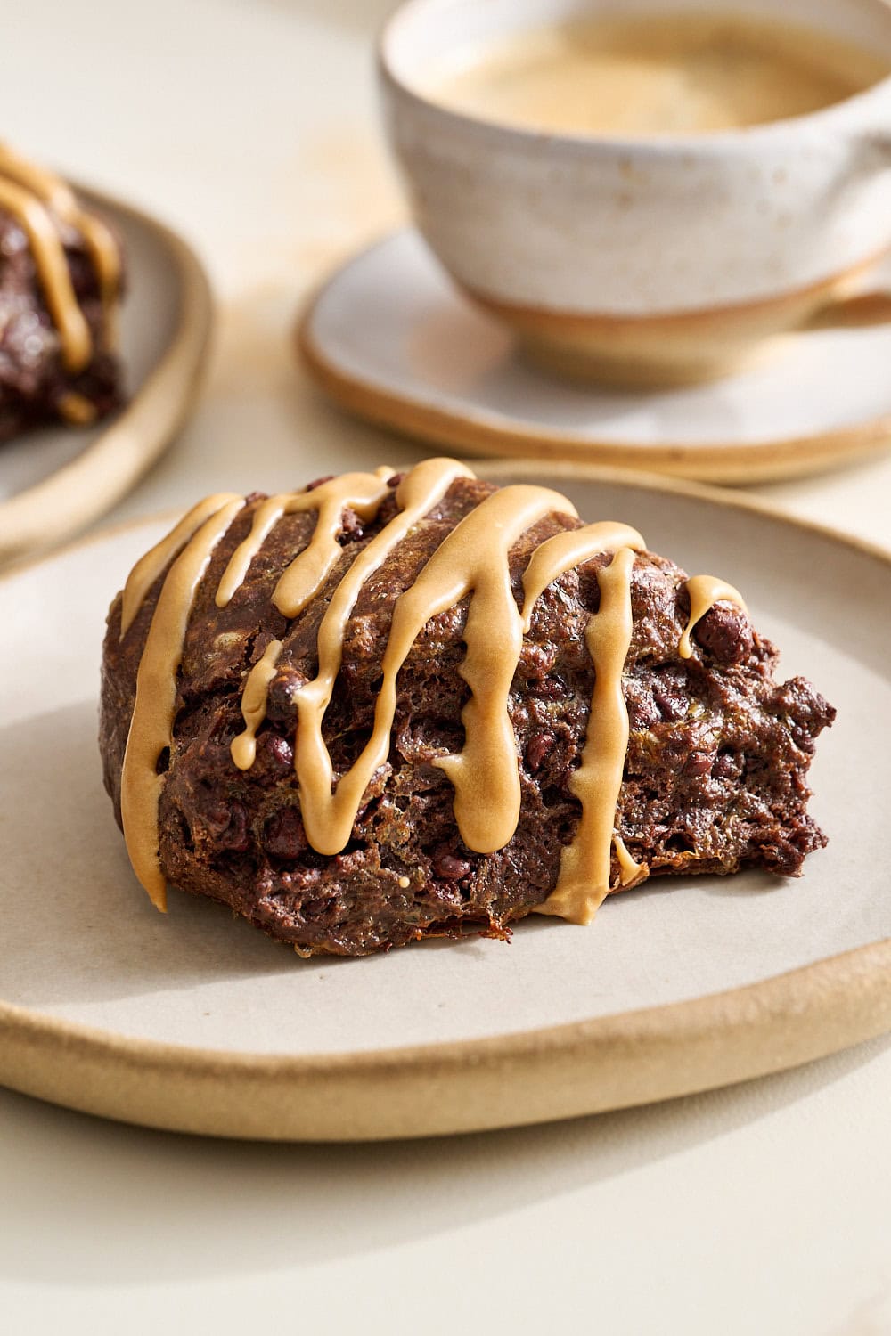 three quarter view of a mocha scone on a small plate with a cup of coffee