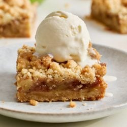 an apple pie bar on a small plate with a scoop of vanilla ice cream on top