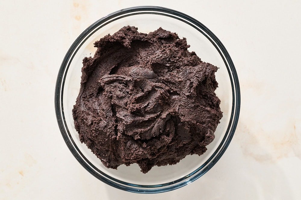overhead view of black cocoa halloween cookie dough in a glass bowl