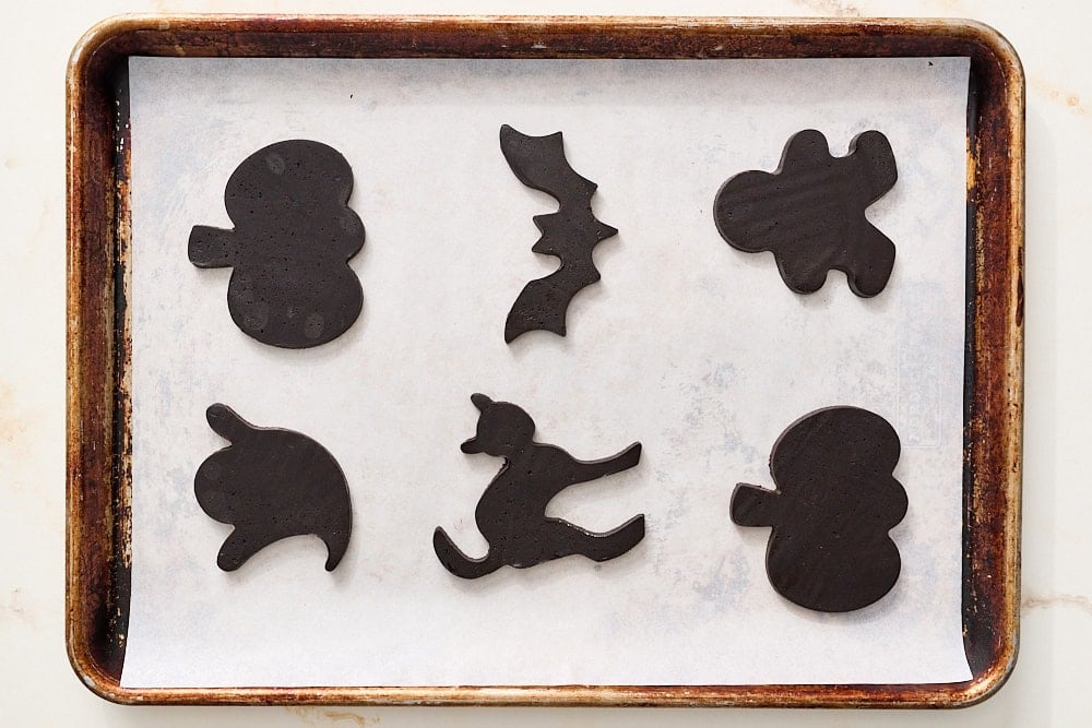 overhead view of black cocoa halloween cookie dough cut into shapes before baking