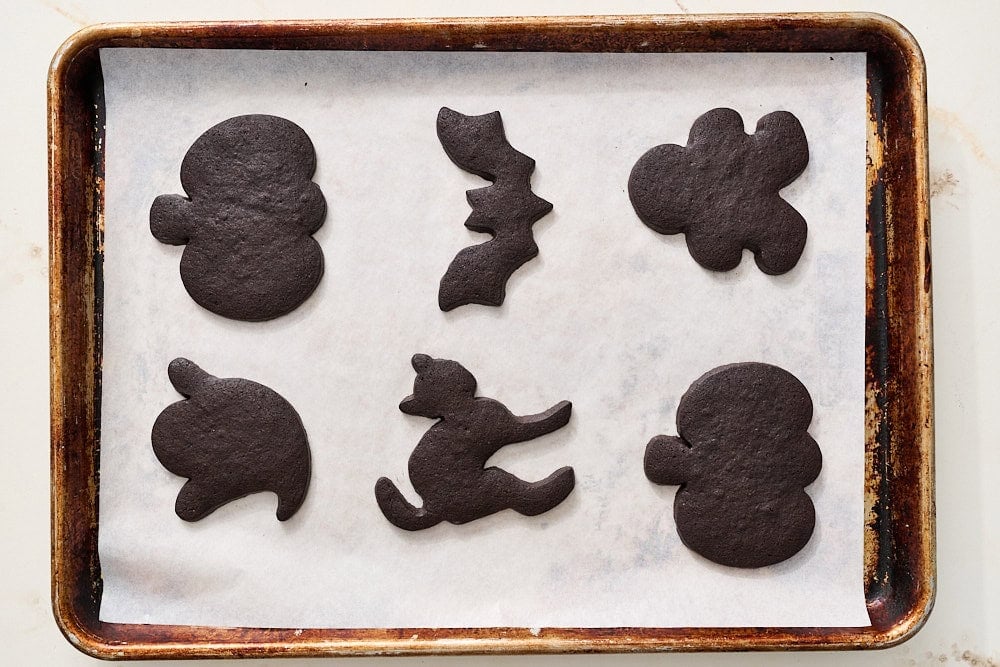 overhead view of black cocoa halloween cookie dough cut into shapes after baking