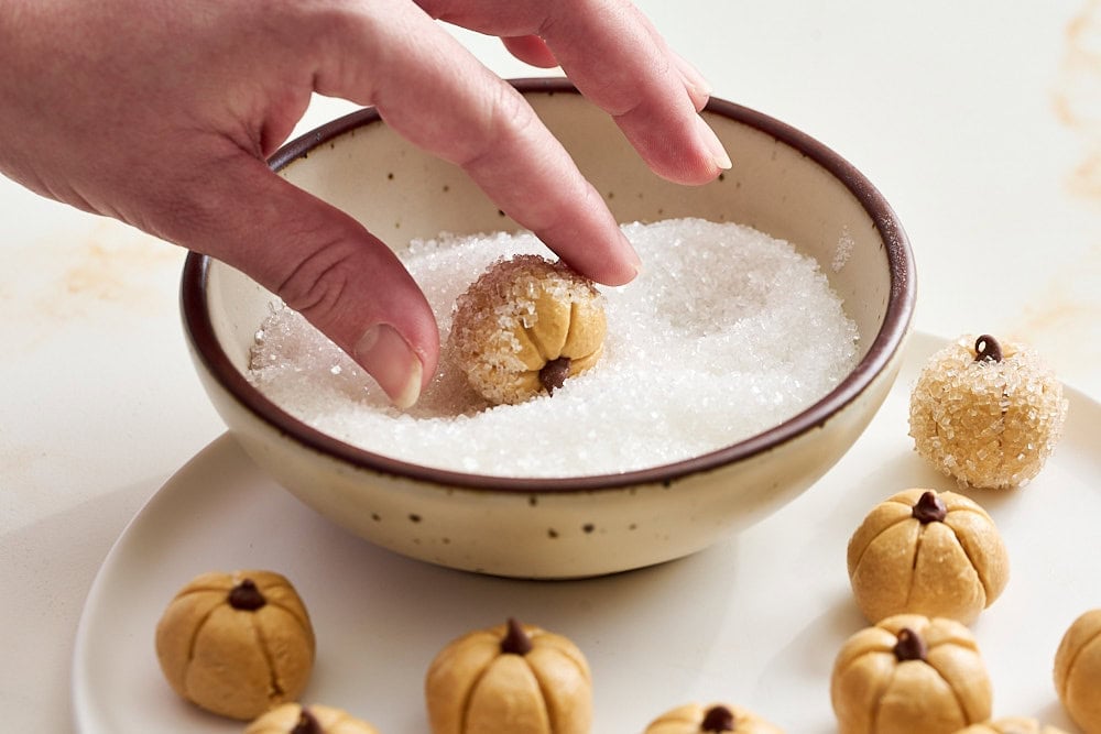 rolling a peanut butter pumpkin in sparkling sanding sugar