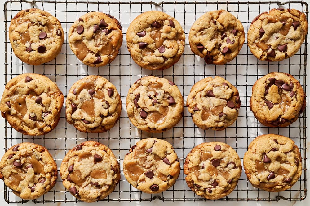 overhead view of batch of peanut butter toffee chocolate chip cookies on a wire rack