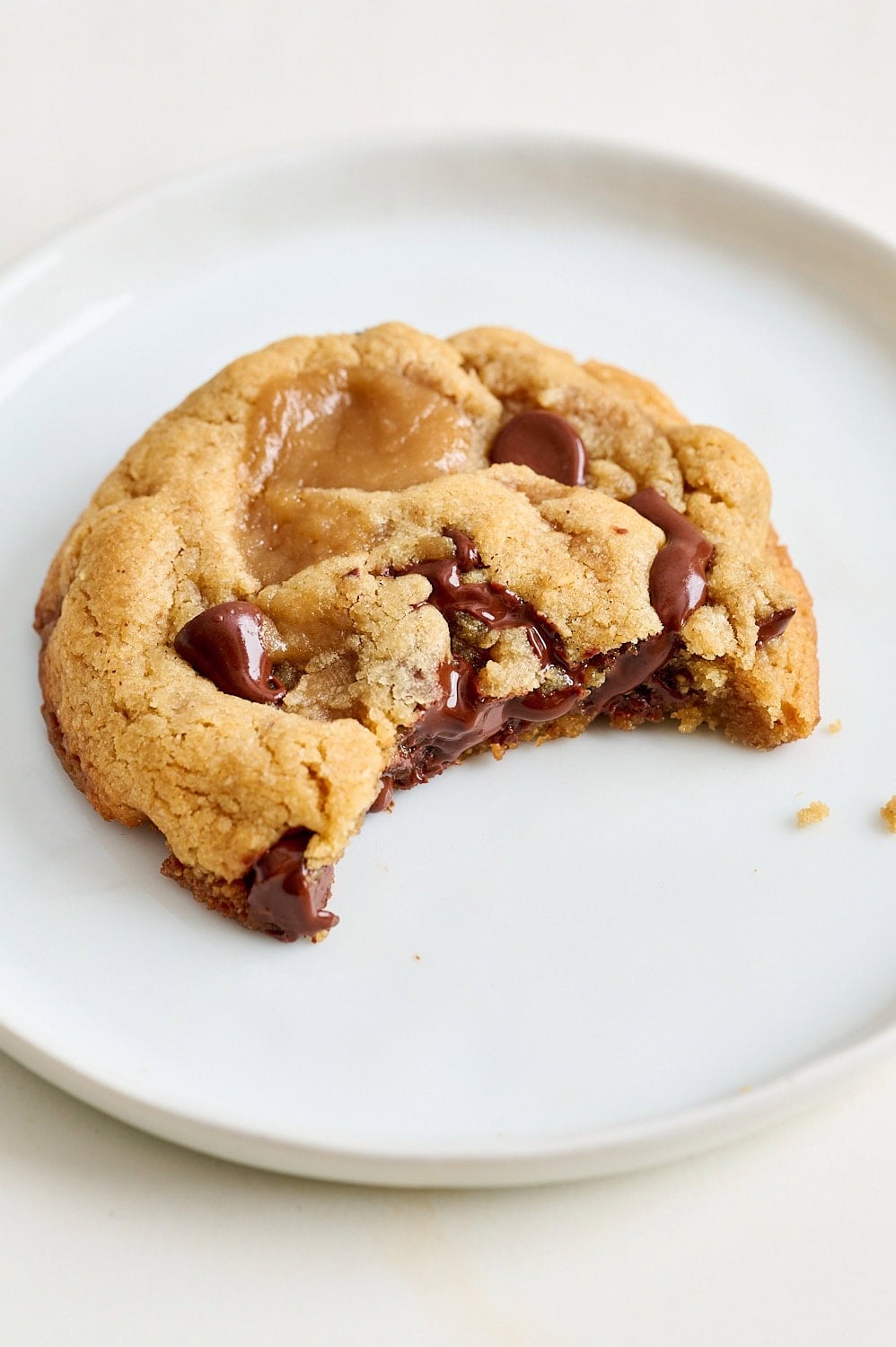 three quarter angle view of a cookie on a small plate with a bite taken out to show the gooey chocolate inside