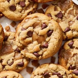 overhead view of many peanut butter toffee chocolate chip cookies spread out on a marble surface